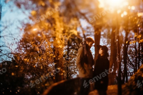 Preview: happy stylish couple hugging and holding hands with tender under yellow lantern