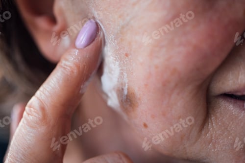 Preview: Close-up of an elderly woman face with moisturizer on her cheek.