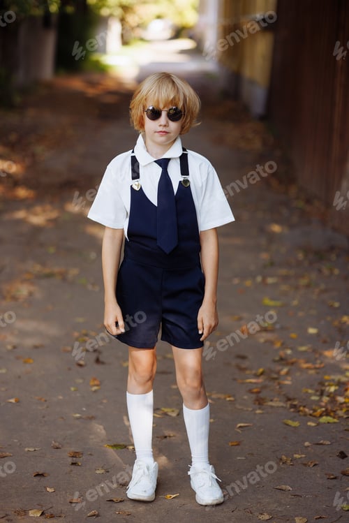 Preview: Portrait of a young schoolgirl in black round sunglasses and school uniform. Back to school.