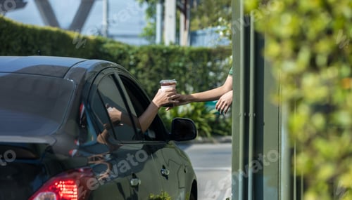 Preview: Hand Man in car receiving coffee in drive thru fast food restaurant.