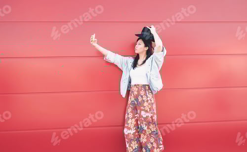 Preview: Happy Asian girl taking selfie with mobile phone outdoor
