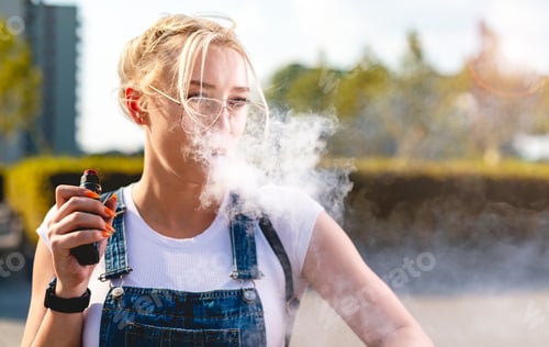 Preview: Portrait of young woman vape an electronic cigarette outdoor