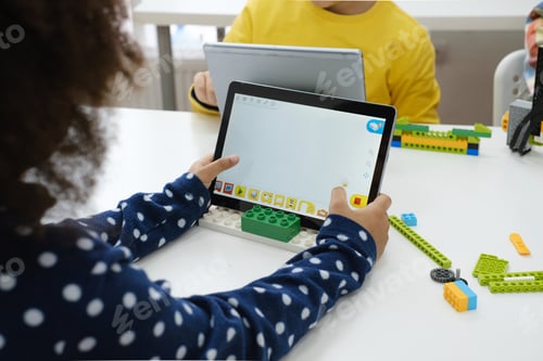 Preview: Multi ethnic children at technology lesson coding robot on tablet