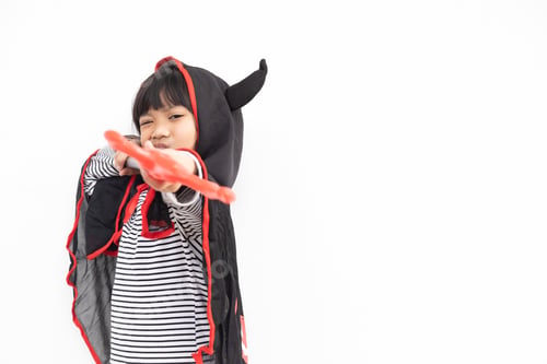 Preview: Asian child girl in demon costume holding black and red trident, happy halloween concept