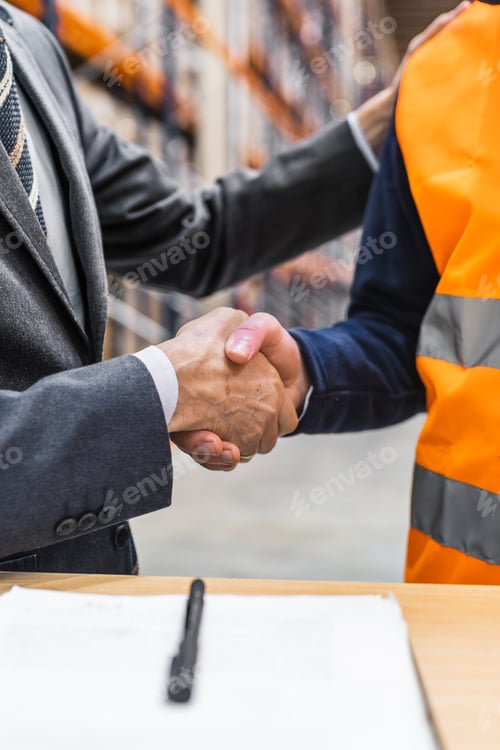 Preview: Manager shaking hands with warehouse worker after signing contract