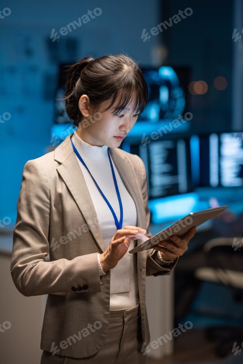 Preview: Young Asian businesswoman in formalwear scrolling in tablet