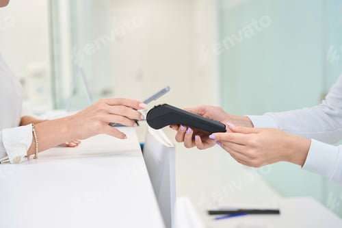 Preview: Female client making contactless payment at reception desk