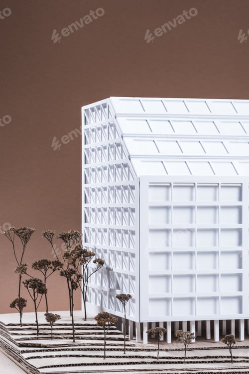 Preview: close up view of white building model with miniature trees on brown backdrop