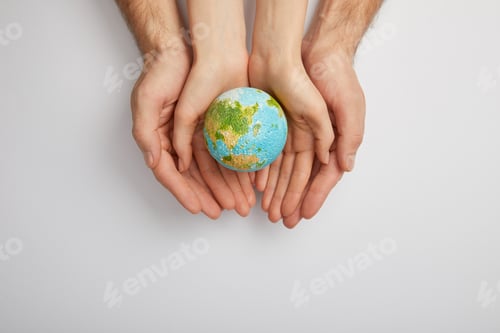 Preview: top view of man and woman holding planet model on grey background, earth day concept