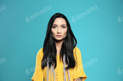 Preview: Portrait of young hippie woman with boho makeup in stylish outfit on color background
