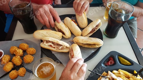 Preview: Group of friends share sandwiches and snacks at the pub, chips and drinks on the table