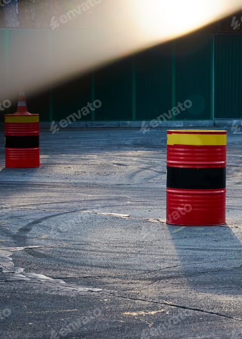 Preview: Black car tire skid track on asphalt road track. Tin barrels of red, black, yellow color