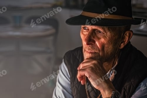 Preview: the wrinkled face of an elderly man in a hat sits lost in thought