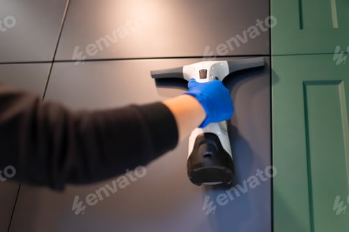 Preview: Cleaning company employee cleans kitchen cabinets with window vacuum cleaner