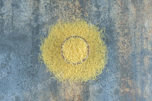 Preview: Vermicelli pasta scattered from a full bowl , on the marble background