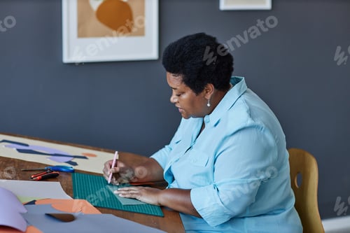Preview: Side view of aged African American craftswoman working over new artwork