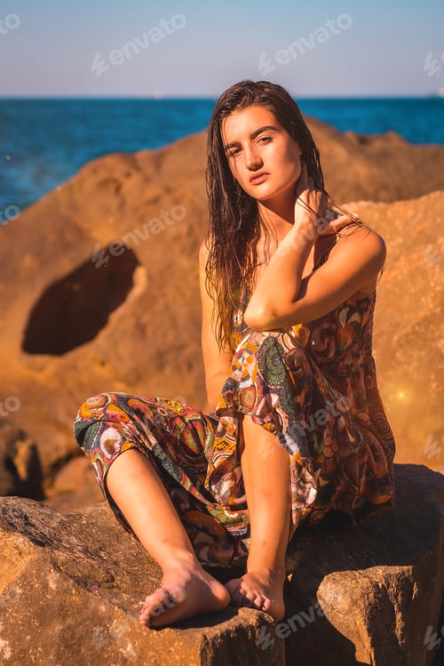 Preview: A young brunette with wet hair and a floral dress by the sea, summer llifestyle