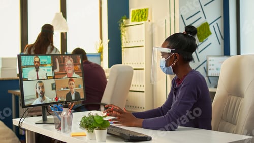 Preview: Black manager with protective mask having videocall with team