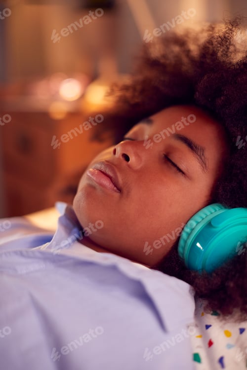 Preview: Boy Lying On Bed Wearing Wireless Headphones With Eyes Closed Listening To Music Or Audiobook