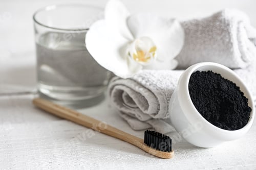 Preview: Close up of black natural teeth whitening powder and toothbrush.
