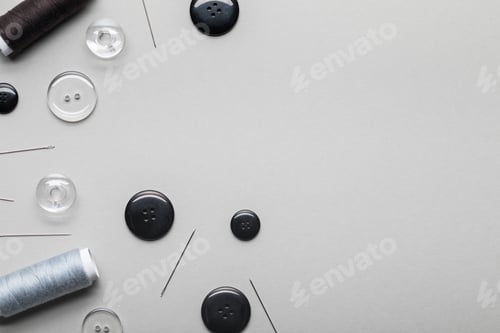 Preview: top view of clothing buttons, needles and thread coils isolated on grey with copy space