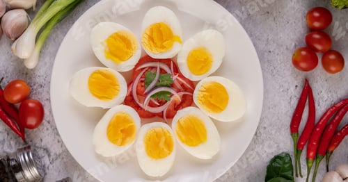 Preview: Half boiled egg in a white plate with tomatoes and spring onions.