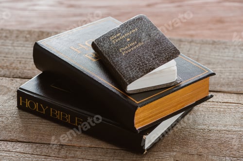 Preview: close-up shot of stacked holy bibles with new testament book on wooden surface