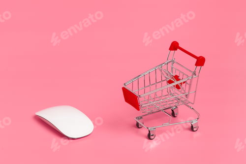 Preview: Shopping cart and computer mouse on a pink background during a creative workspace setup