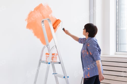 Preview: Smiling middle-aged woman painting interior wall of home. Renovation, repair and redecoration