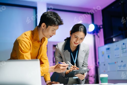 Preview: Asian business colleagues collaborating in modern office, discussing documents and strategy,