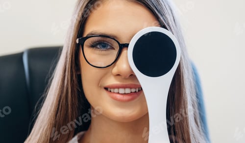 Preview: Pretty young woman is checking her vision in the ophthalmologist cabinet