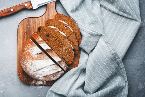 Preview: Rye sourdough bread with raisins, sliced pieces on wooden cutting board, bread knife