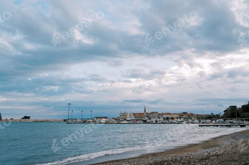 Preview: Resort town with a marina on the seashore against a cloudy sky
