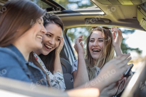 Preview: Friends laughing together inside a car.
