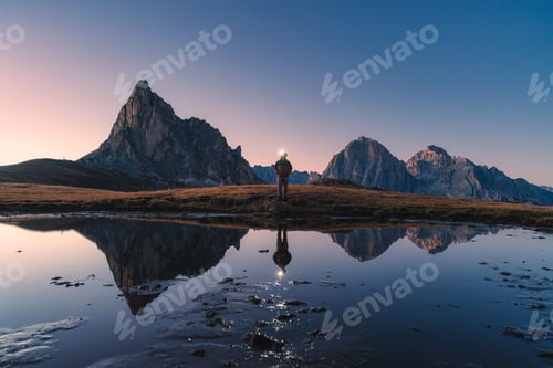 Preview: Ra Gusela mountain with male hiker headlamp and pond reflection in Passo Giau, Dolomites