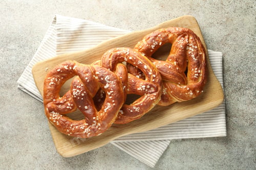 Preview: Tasty pretzels with salt on grey table, top view