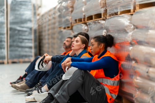 Preview: Exhausted warehouse workers resting during a hard break in logistics facility