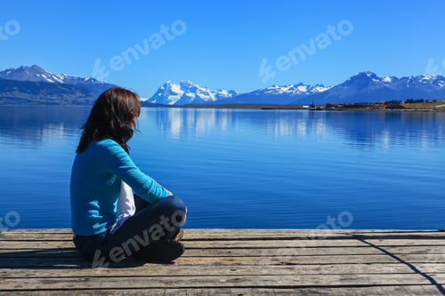 Preview: Young woman sitting on a pier enjoying the view