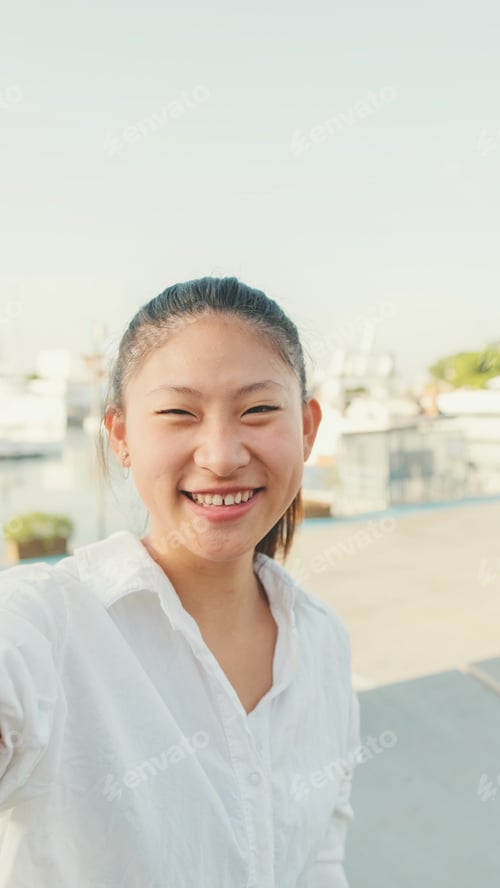 Preview: Close up, young woman video chatting using mobile phone while sitting in port