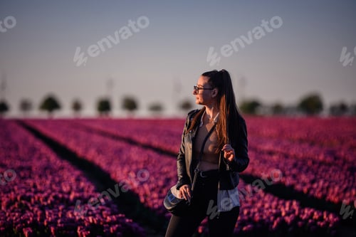 Preview: Woman in Leather Jacket Standing in Purple Tulip Field
