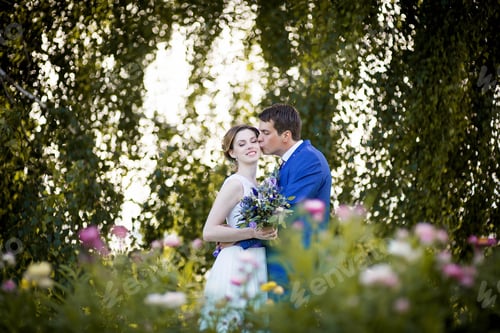 Preview: Happy young bride and groom in summer garden on wedding day.