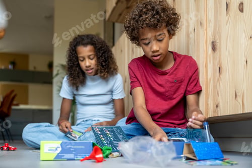 Preview: Mixed race brother and sister playing contently together happy on the floor with games