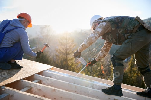Preview: Male builder doing thermal insulation on roof of wooden frame house by polyurethane foam.