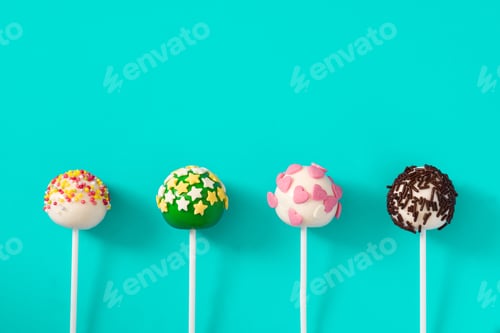 Preview: Four colorful cake pops with star and heart decorations standing against turquoise background