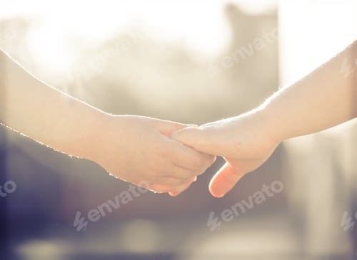 Preview: little girl and boy hold hands close-up, against the backdrop of a green garden.