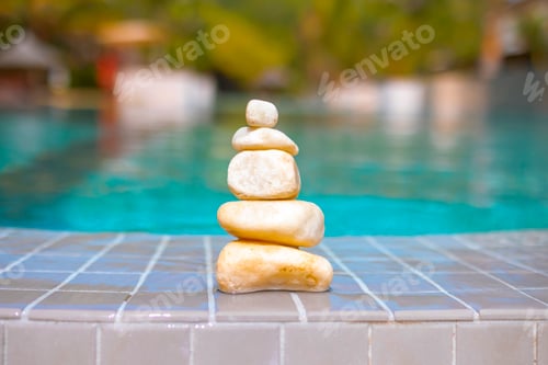 Preview: pyramid of stones by pool, balanced zen stones, spa and relax concept