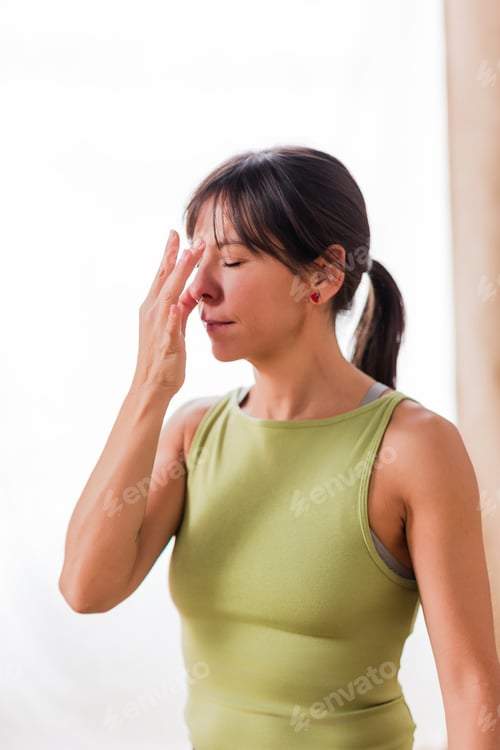 Preview: Hispanic woman practicing nadi shodhana pranayama yoga breathing