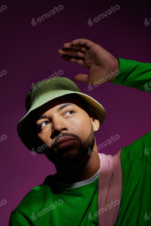Preview: young stylish man with earring and slightly raised hand on purple background, fashion concept