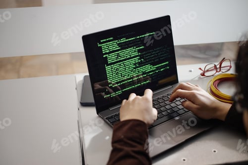 Preview: Young Adult Man Typing Code on Laptop Computer in Office Setting