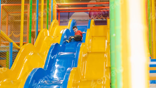 Preview: A boy rides from the children's slides on the playground in the play center. Active leisure